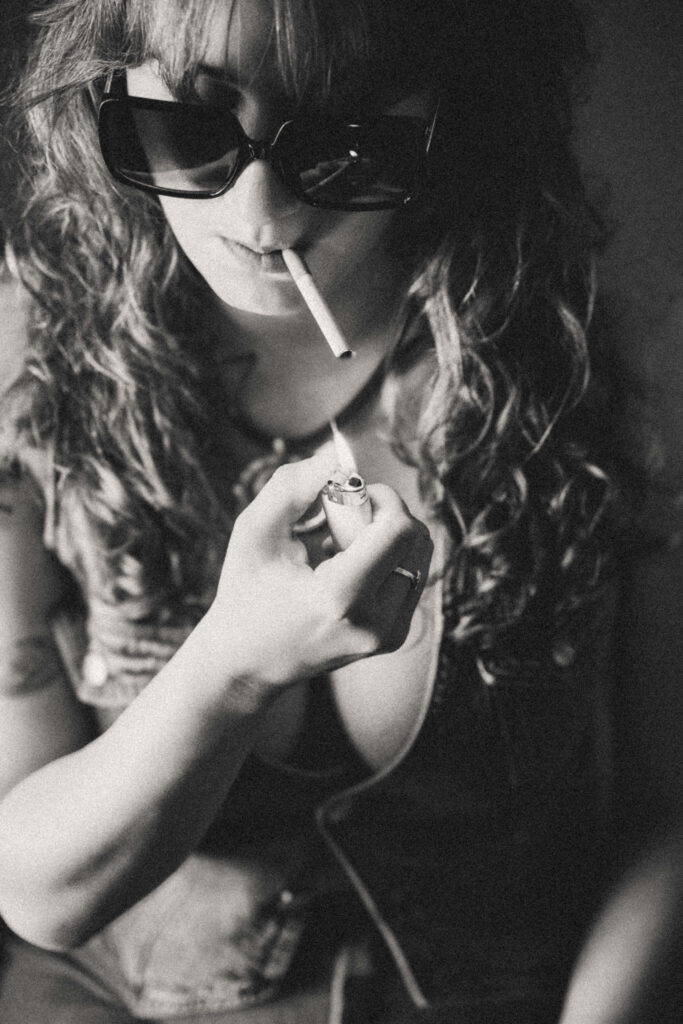 Moody 1970s boudoir portrait with dramatic lighting and authentic expression, the cigarette photo.